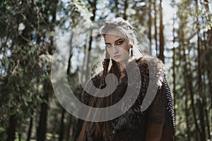 Viking woman wearing traditional warrior clothes in a deep mysterious forest.