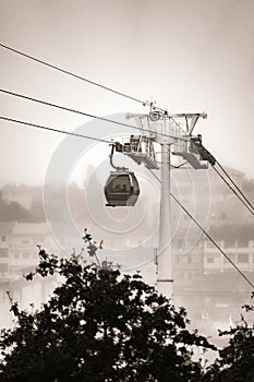 A Vilanova de Gaia cable car gondola suspended on hanging steel cables ascending under a cloudy sky with the classic Gaia photo