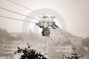 A Vilanova de Gaia cable car gondola suspended on hanging steel cables ascending under a cloudy sky with the classic Gaia photo