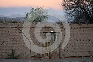 Under a wonderful sunrise light, abandoned adobe house with a wooden door. Mountains in the horizon photo