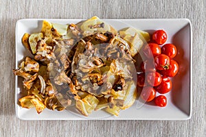 Village breakfast - fried potatoes and mushrooms with tomatoes on white plate