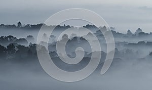 Village buildings houses and trees in low lying dense fog clouds moody morning haze in Gemeinlebarn Lower Austria