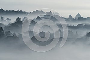 Village buildings houses and trees in low lying dense fog clouds moody morning haze in Gemeinlebarn Lower Austria