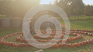Village children play in the fall. Pumpkins are stacked in spiral on the ground.