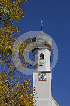 village church in gmund, golden beech leaves and blue sky, bavaria photo