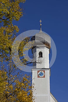 village church in gmund, golden beech leaves and blue sky, bavaria