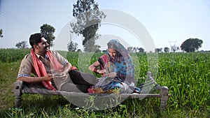 A village couple sitting on a woven cot in the village - modern village couple, modern lifestyle