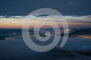 Village in early morning with thick mist or cloud and electric light in forest