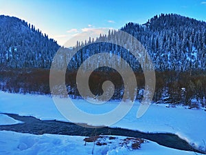 Village by Frozen River at Winter Sunrise