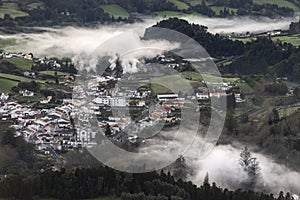 Village of Furnas at sunrise with a fog mist of gases and steams from several fumaroles, calderas and thermal pools