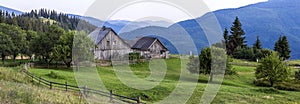 Village houses on hills with green meadows in summer day. House