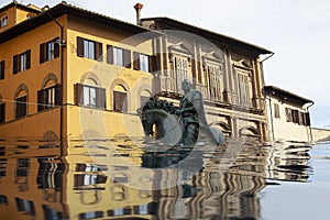 Village houses and statue in floodwater. Road with overflown water.