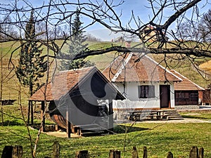 Village huts with grassy green surrounding and wooden wine barrel in the yard