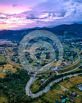 Village in the mountains, old bridge viaduct, lilac sunset aerial view