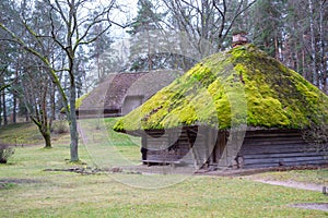 Village. Old wooden log house. View with window, front door and with moss on the roof.