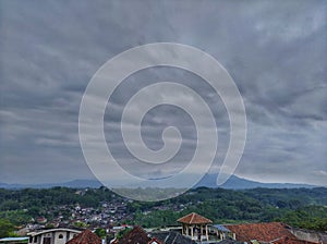 village with panorama of forest, mountains and cloudy sky