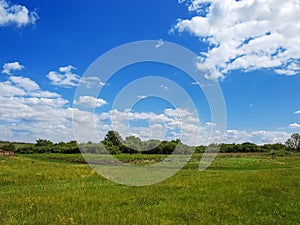 Village panorama spring - spacious green meadow, blue sky with c