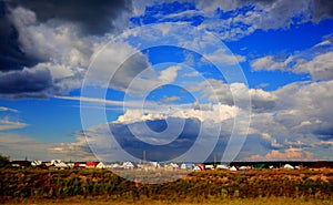 The village at the setting sun and sky with storm clouds