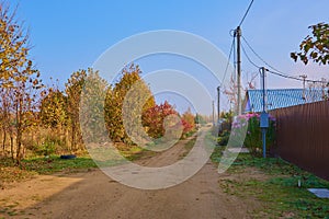 Village street with bright autumn trees under a clear blue sky