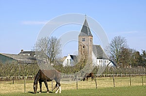Village view with ancient church, horses and fruit yard