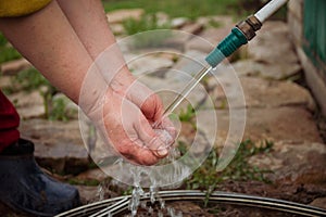 village woman washes her hands under running water from a tap close-up