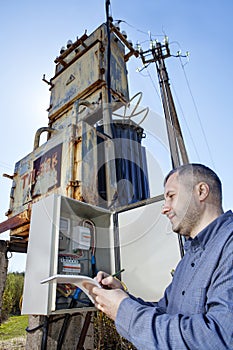 Villager technician writing reading of electricity meter on clipboard.