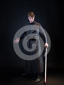 A villain with a red lightsaber, a young man in a long robe does fighting poses,