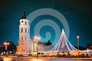 Vilnius, Lithuania. Amazing Bold Bright Blue Starry Sky Gradient Above Christmas Tree On Background Bell Tower Belfry Of