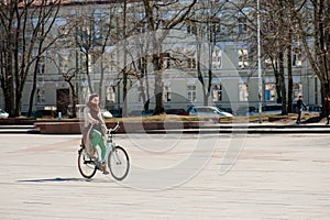 VILNIUS, LITHUANIA - April 10, 2012: Woman Riding Bike in Vilnius, Lithuania. Cathedral Square