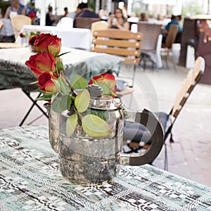 Vilnius Old Town, Red roses in a silver coffee pot on a table in a street cafe for decoration