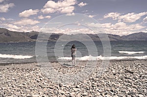 Vinatge Ocean waves and rocks beach with a woman standing at the shore