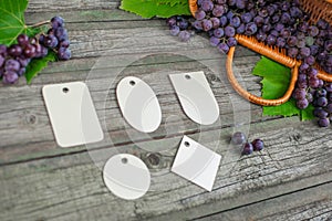 Vine with grapes and leaves on vintage rustic wooden table. Set of differents paper tags template
