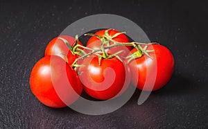 vine red tomatoes on black slate background, close up