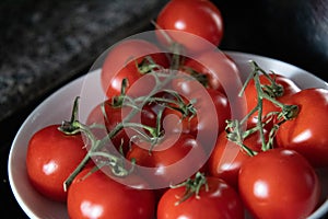 Vine ripe tomatoes in a white bowl on a granite counter