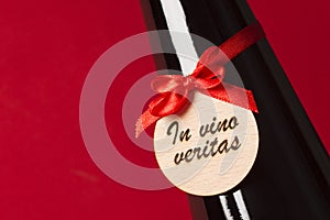 In vino veritas on wine bottle on red background photo