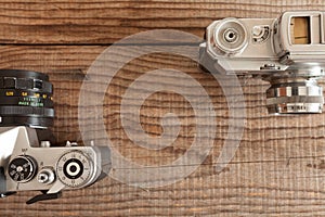 Vintage 35mm film cameras both lying over a dated wooden background