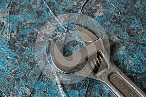 Vintage adjustable spanner on a blue background