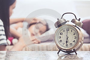 Vintage alarm clock on background of mother taking care child