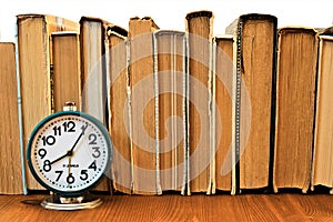 Vintage alarm clock on the background of a stack of old books