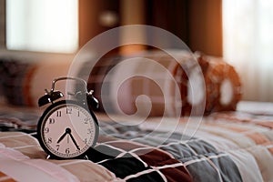 Vintage Alarm clock on bedroom in the morning with sunrise at the windows background.