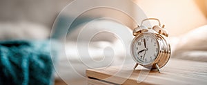 The vintage alarm clock on a bedside table in a cozy bedroom setting..AI generated image