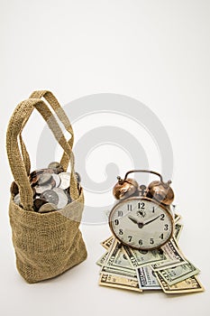 Vintage alarm clock cash coins bag time investment strategy