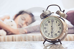 Vintage alarm clock on cute asian child girl sleeping in the bed
