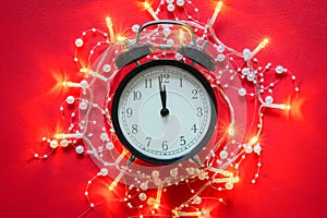 Vintage alarm clock showing midnight and garland lights around