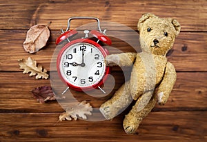 Vintage alarm clock, toy bear and autumn leaves, back to school, fall background