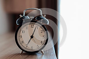 Vintage Alarm clock on the wood headboard at the bedroom in the morning with sunlight as windows background