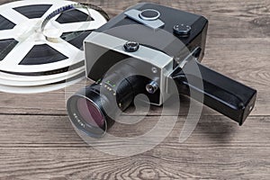 Vintage amateur movie camera against of films on wooden surface