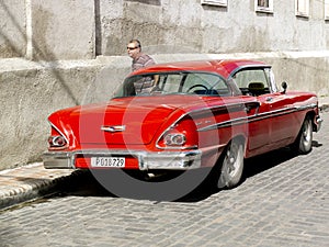 Vintage american red car in a paved cuban street.