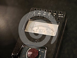 Vintage analog multimeter electrical tester with needle gauge and range sockets black plastic case with dial display showing volts