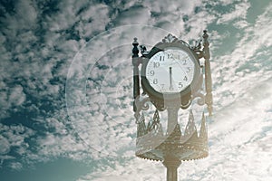 Vintage analogue clock against sunset with beautiful clouds.